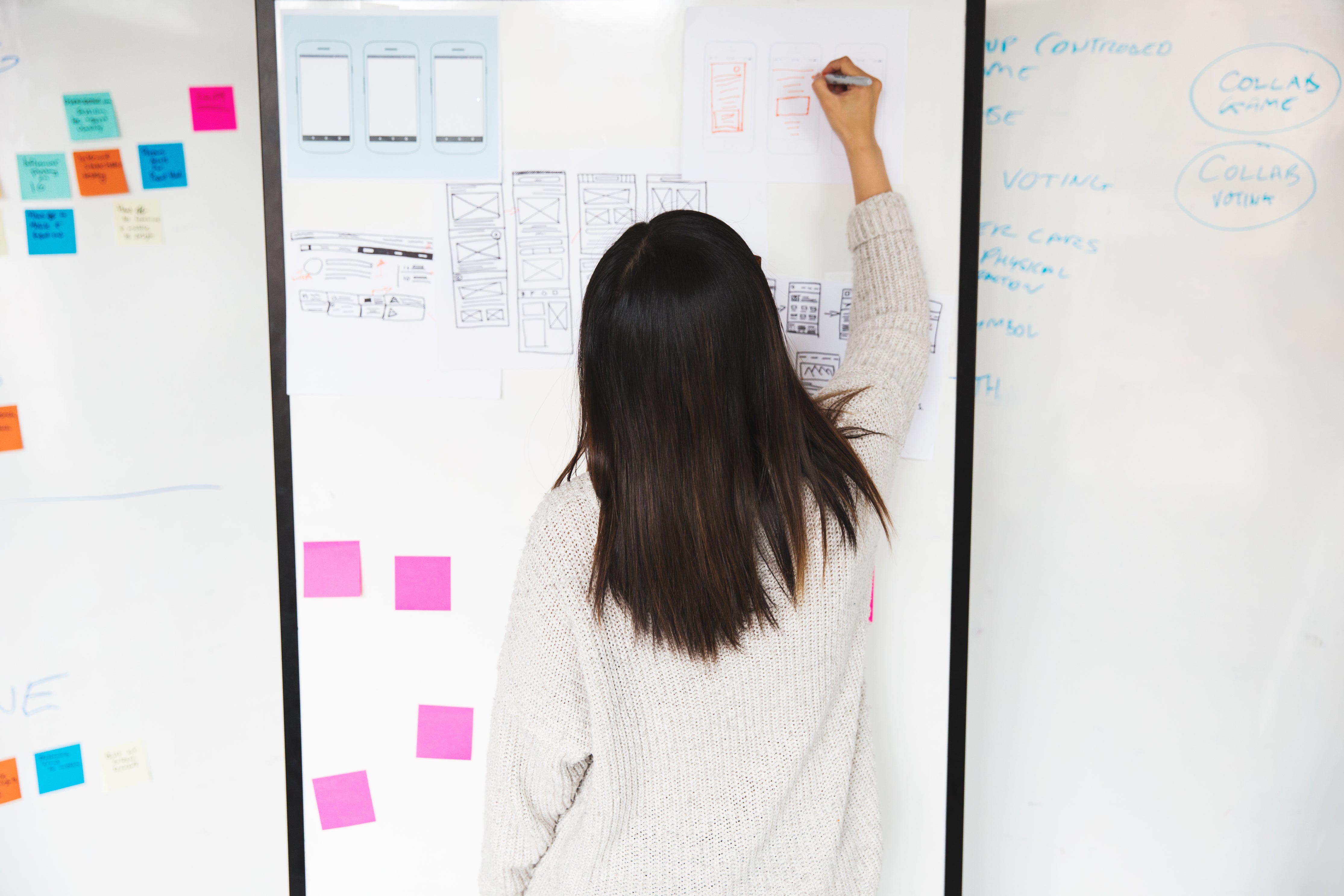 Person brainstorming ideas using a whiteboard and colorful sticky notes