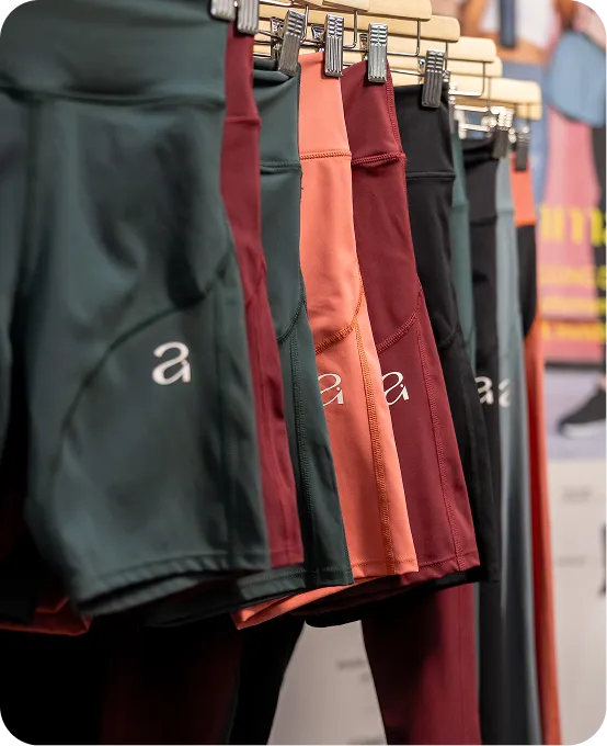 Row of athletic shorts in various colors hanging on wooden hangers in a store.