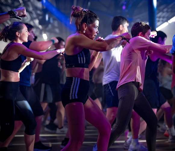 Group of people in workout clothing engaged in an indoor fitness class with energetic movements.
