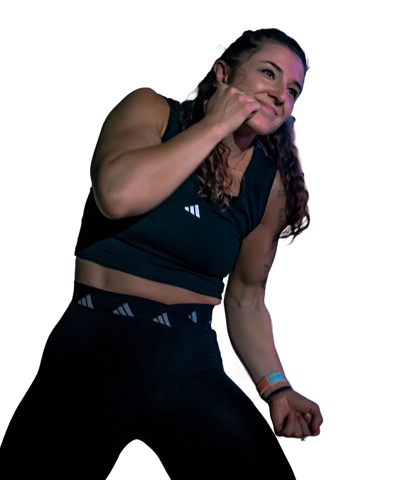 Woman in black athletic wear smiling and posing with clenched fists.