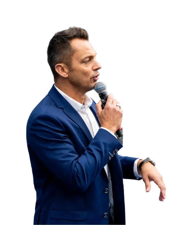 Man in blue suit speaking into a handheld microphone with a focused expression.