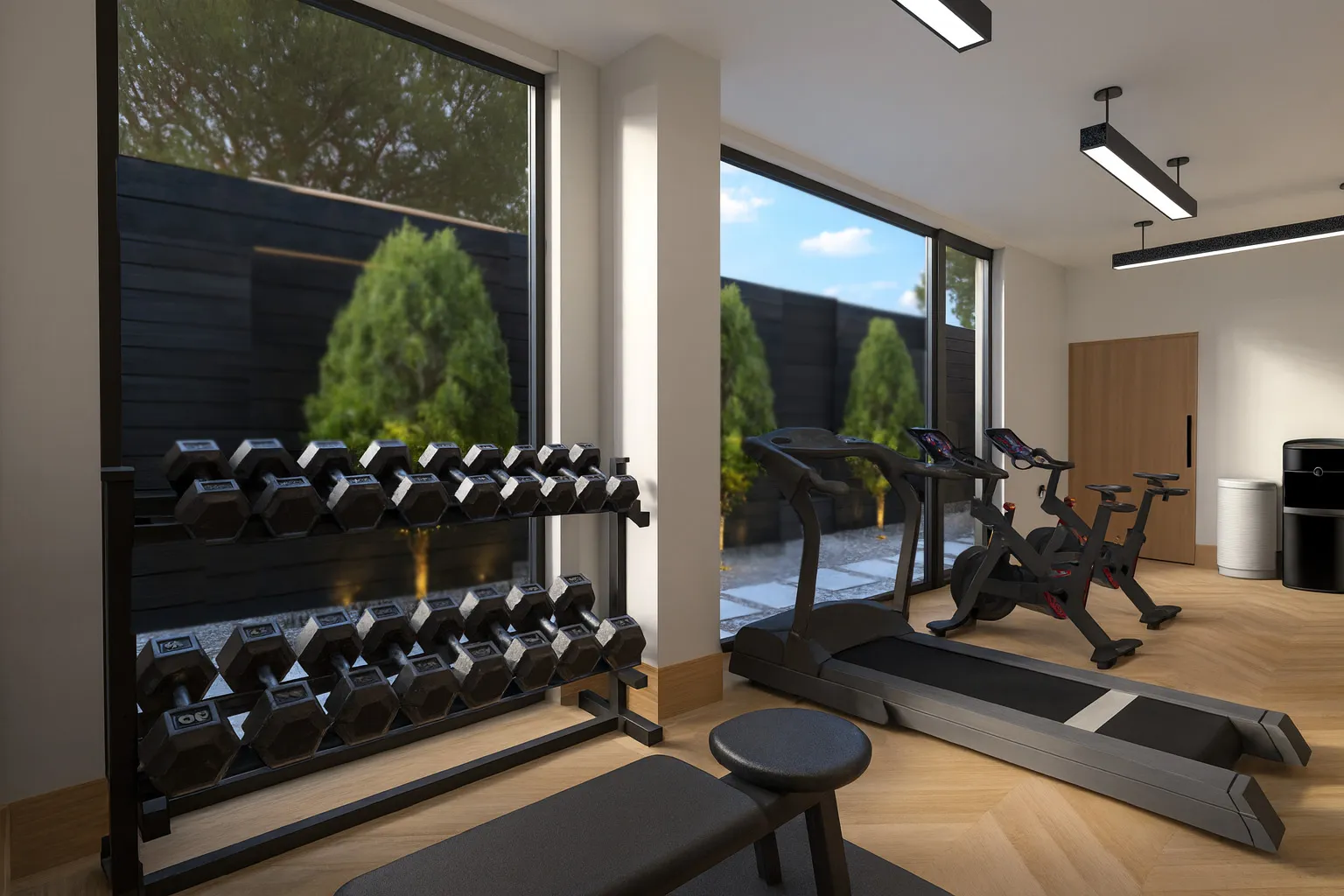 Modern home gym with dumbbells rack, treadmill, exercise bikes, and large windows showing outdoor greenery.