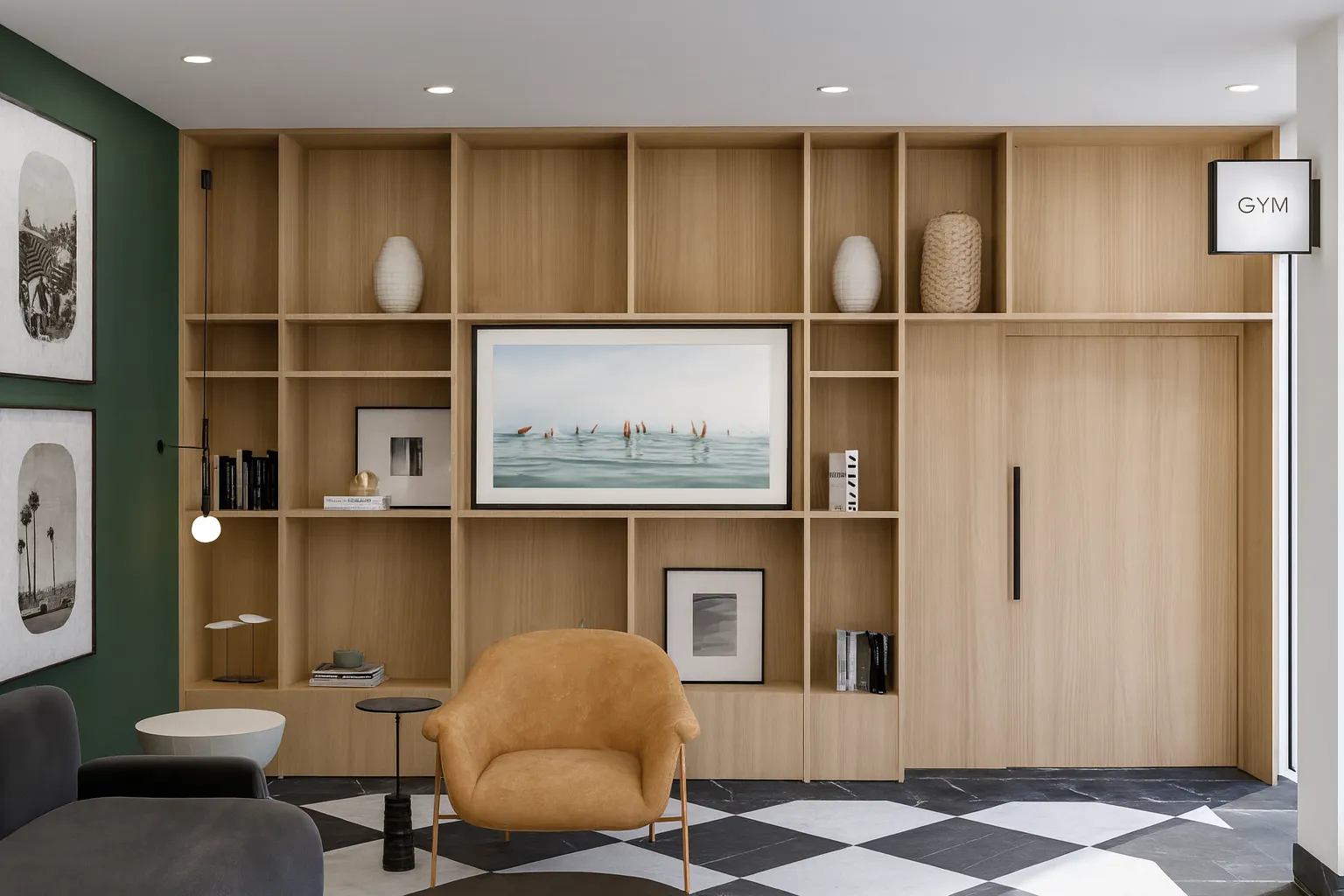 Modern gym entrance with wooden shelves, framed art, a tan armchair, a gray sofa, and a black-and-white checkered floor.