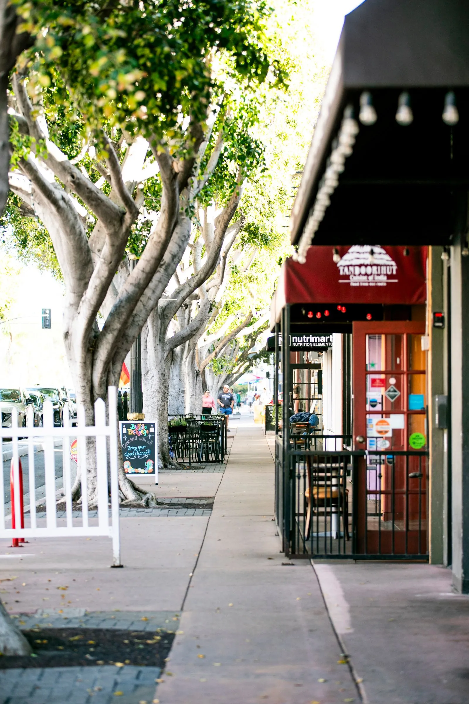 A restaurant with a red awning and a white fence.