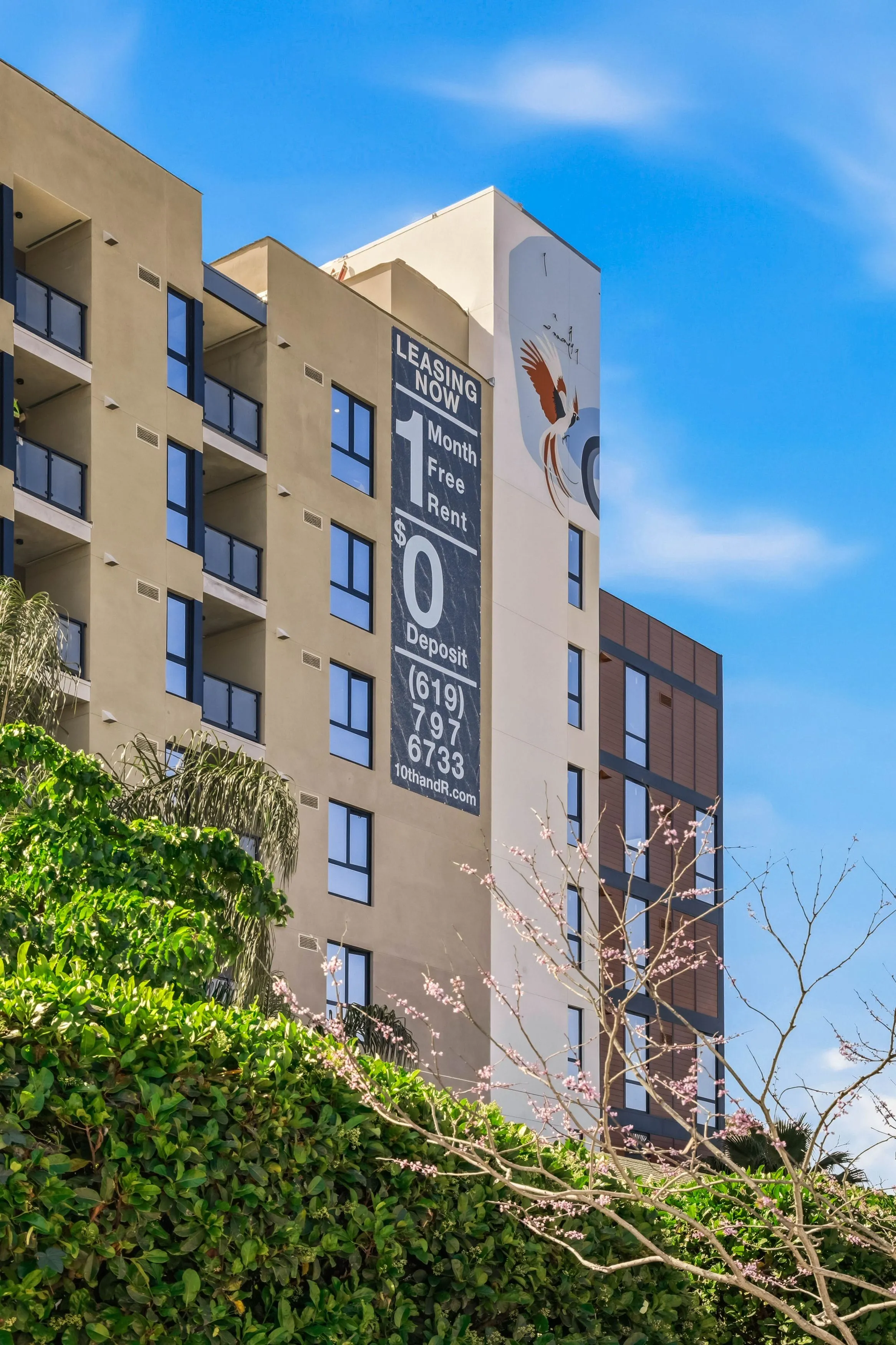 Modern apartment building with a large banner advertising one month free rent and zero deposit, under a blue sky.