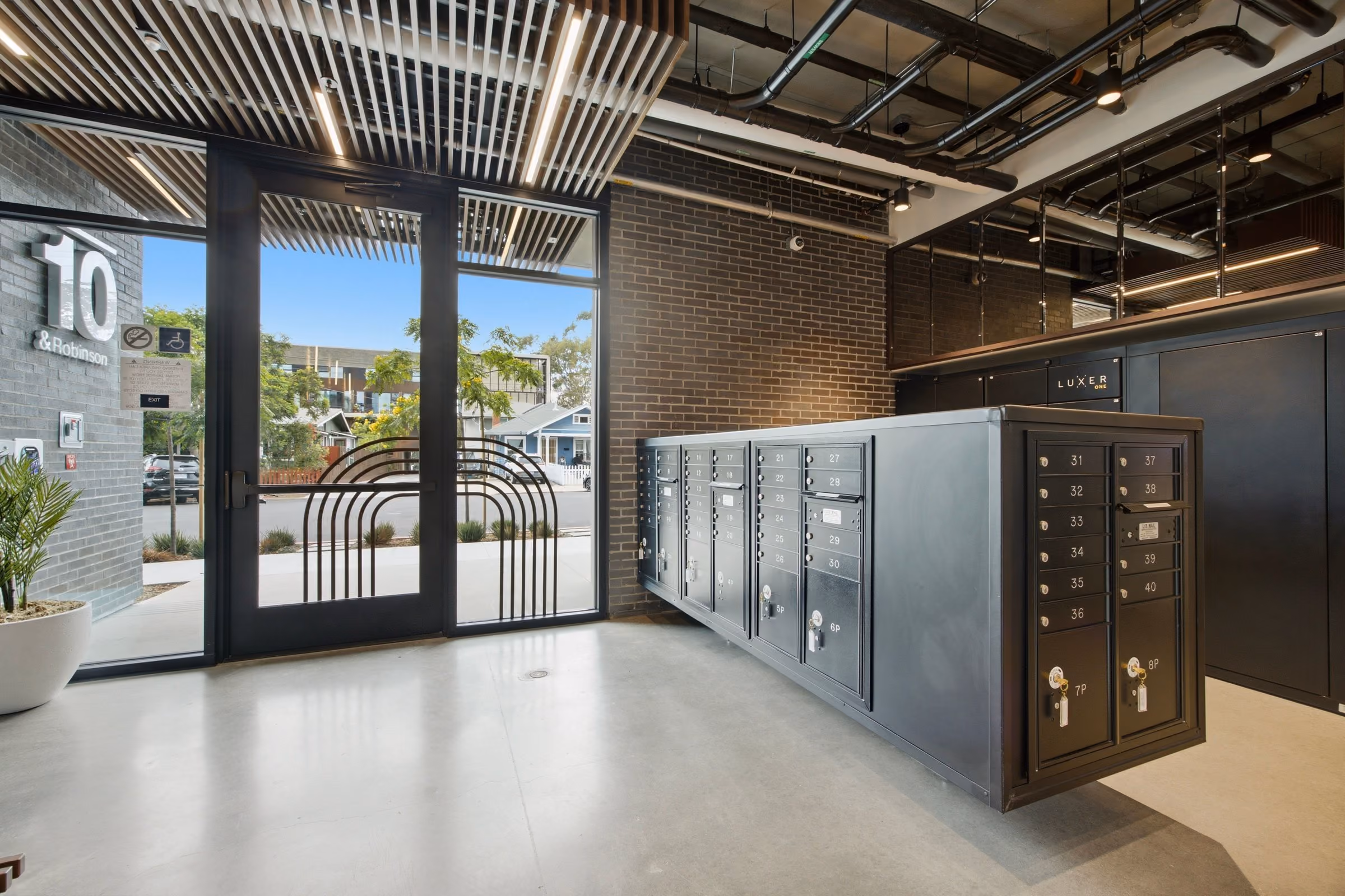 Interior view of a modern mailbox area with numbered lockboxes near glass doors with building number 10.