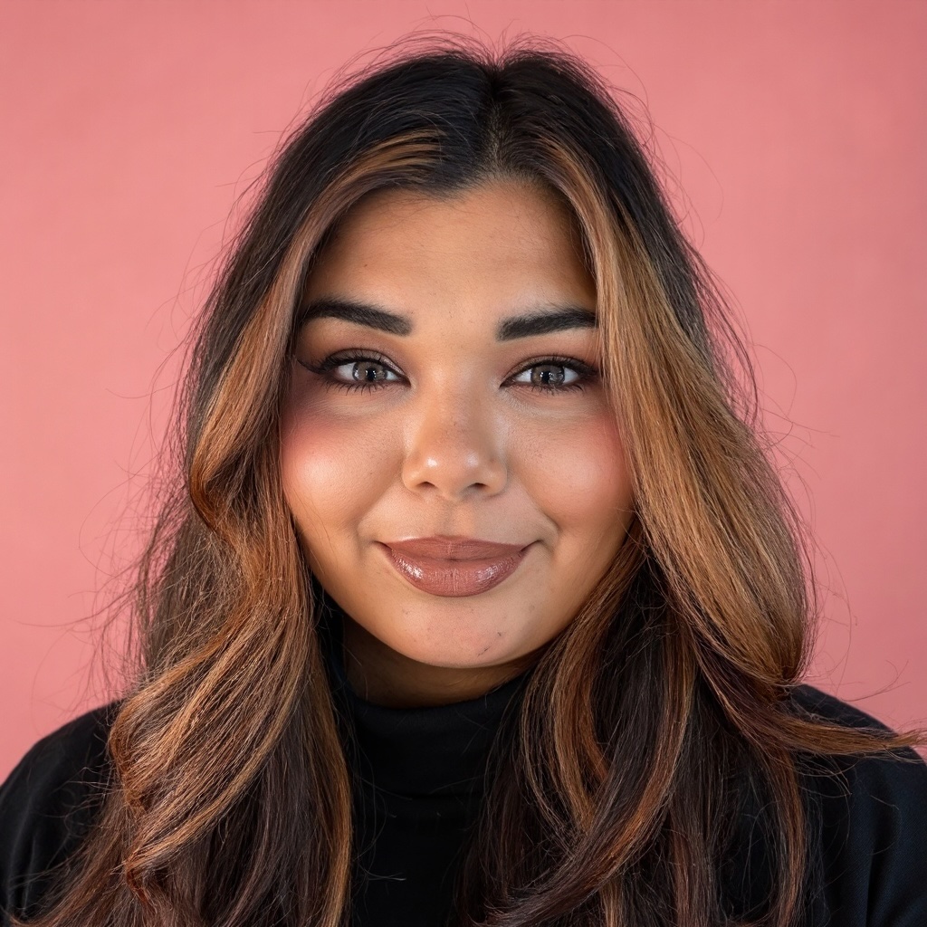 Smiling woman with long brown and blonde hair wearing a black top against a pink background.