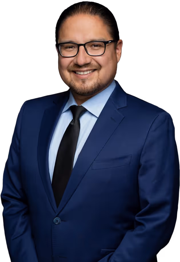 Billy Morin in glasses wearing a blue suit, light blue shirt, and black tie posing against gray backdrop.