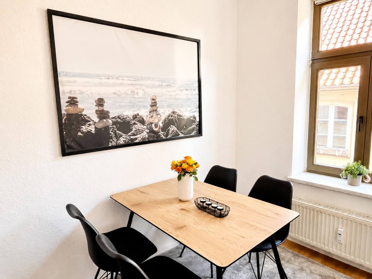 Heller Essbereich mit Holztisch und schwarzen Stühlen in einem Wismarer Apartment