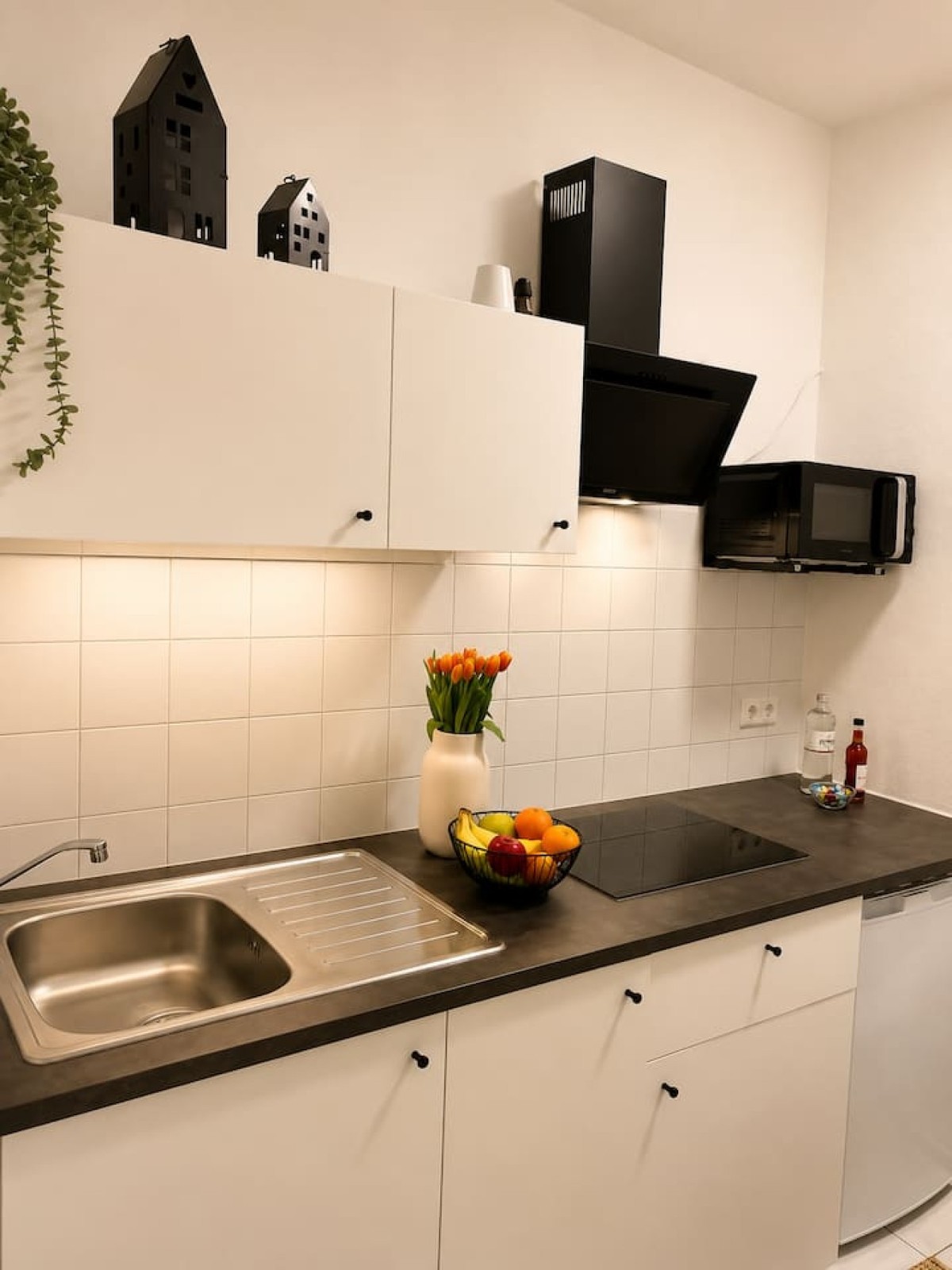 Weiße Küchenzeile mit Spüle, Kochfeld, Dunstabzug und Mikrowelle