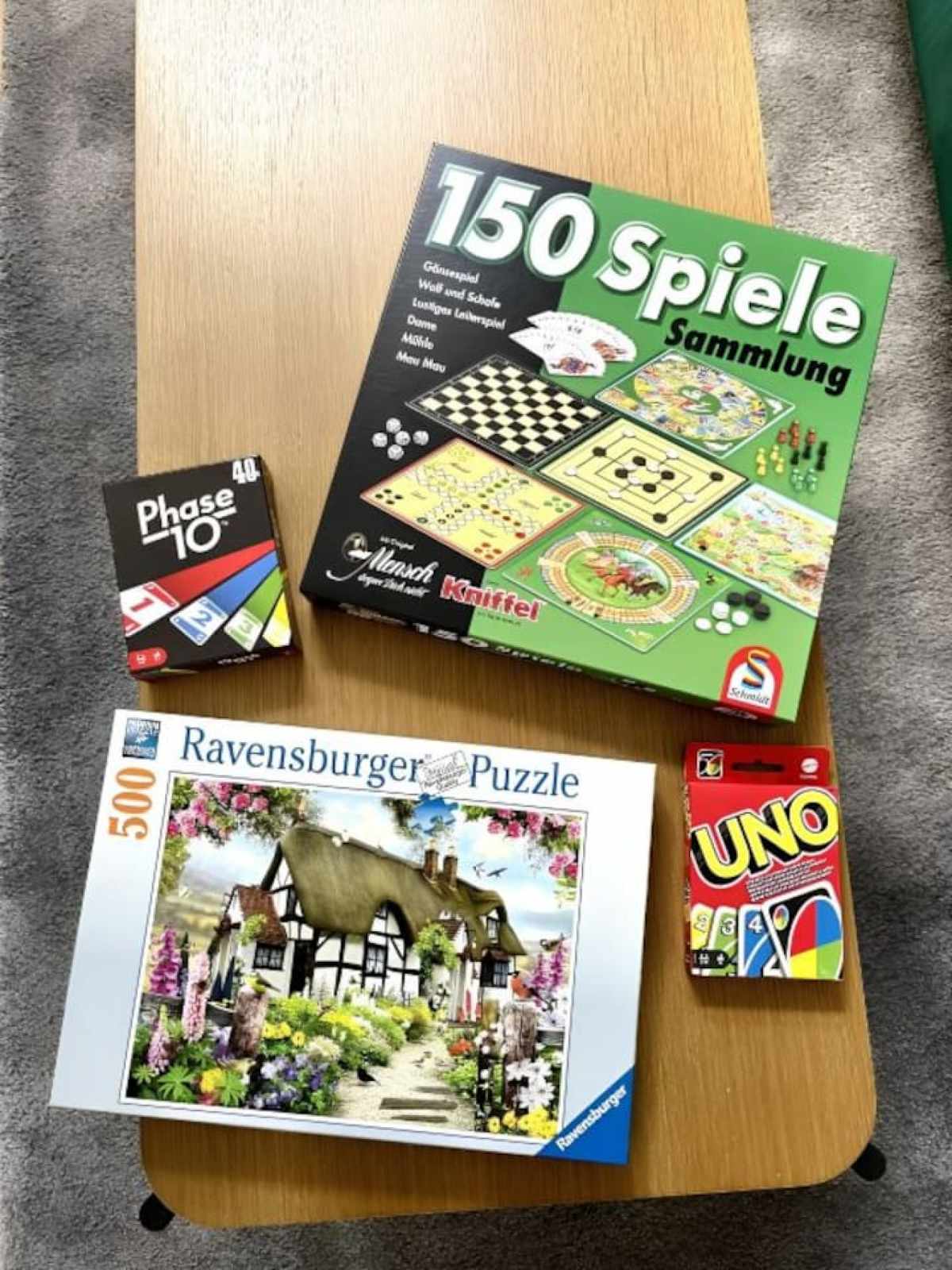 Auswahl an Brettspielen, Kartenspielen und einem Puzzle auf einem Tisch