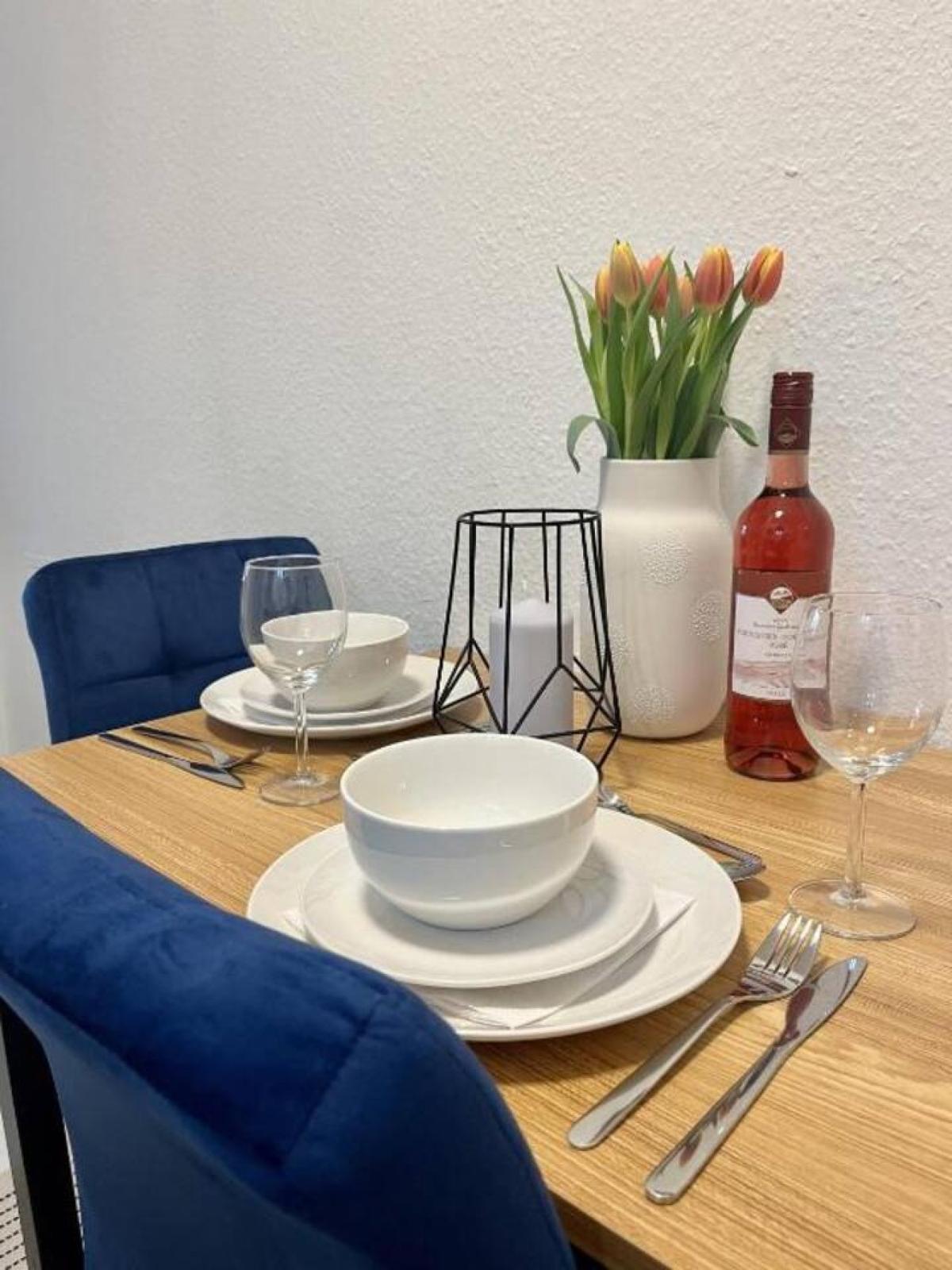 Gedeckter Holztisch für zwei Personen mit blauen Stühlen und Tulpen