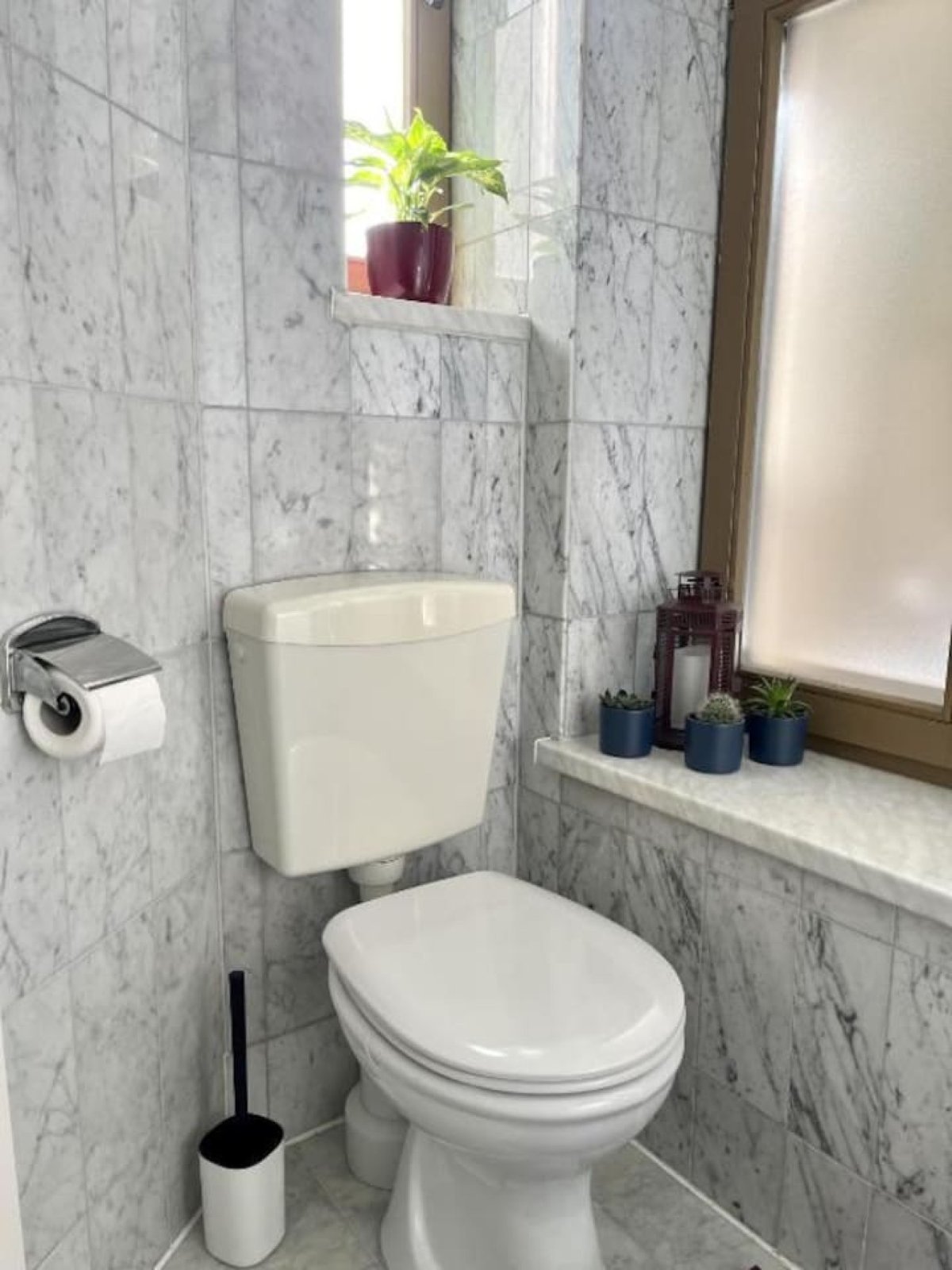 Kompaktes WC mit grauer Wandverkleidung und Fenster