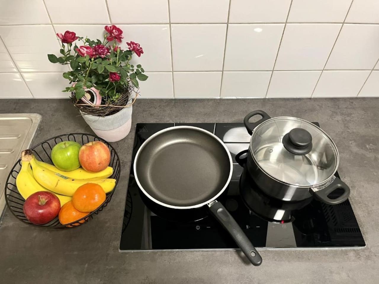 Kochfeld mit Pfanne, Kochtopf und Obstkorb auf der Küchenarbeitsplatte