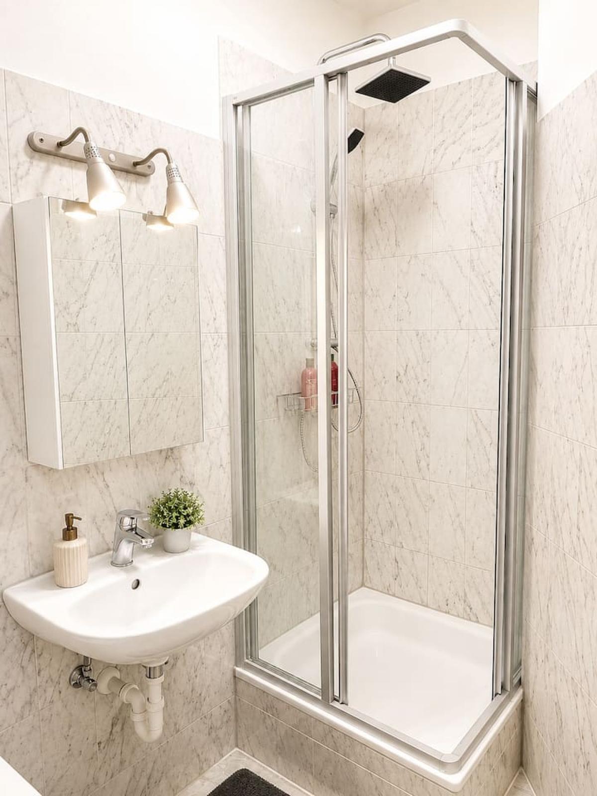 Badezimmer mit Waschbecken, Spiegel und verglaster Dusche