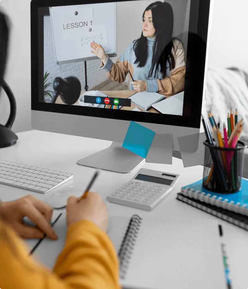 Person taking notes during an online math lesson with a teacher explaining equations on a whiteboard via computer.