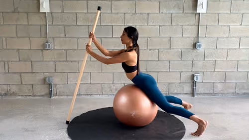 Back extension on Swiss ball using a stick for spinal mobility
