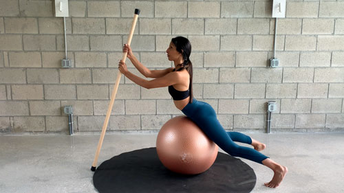 Back extension on Swiss ball using a stick for spinal mobility