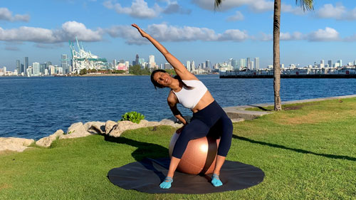 Side to side stretching exercise with a stability ball to improve flexibility and spinal mobility
