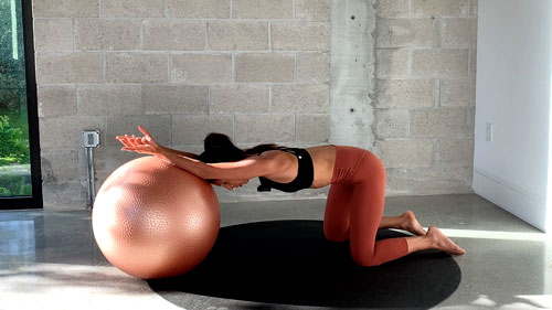Kneeling lat stretch on a stability ball to lengthen the sides and improve flexibility