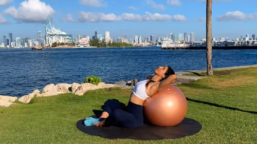 Seated back stretch on the floor using a stability ball for supported spinal extension