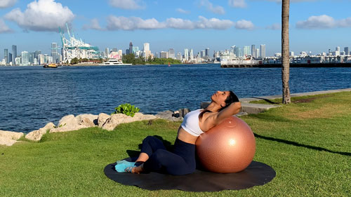 Seated back stretch on the floor using a stability ball for supported spinal extension