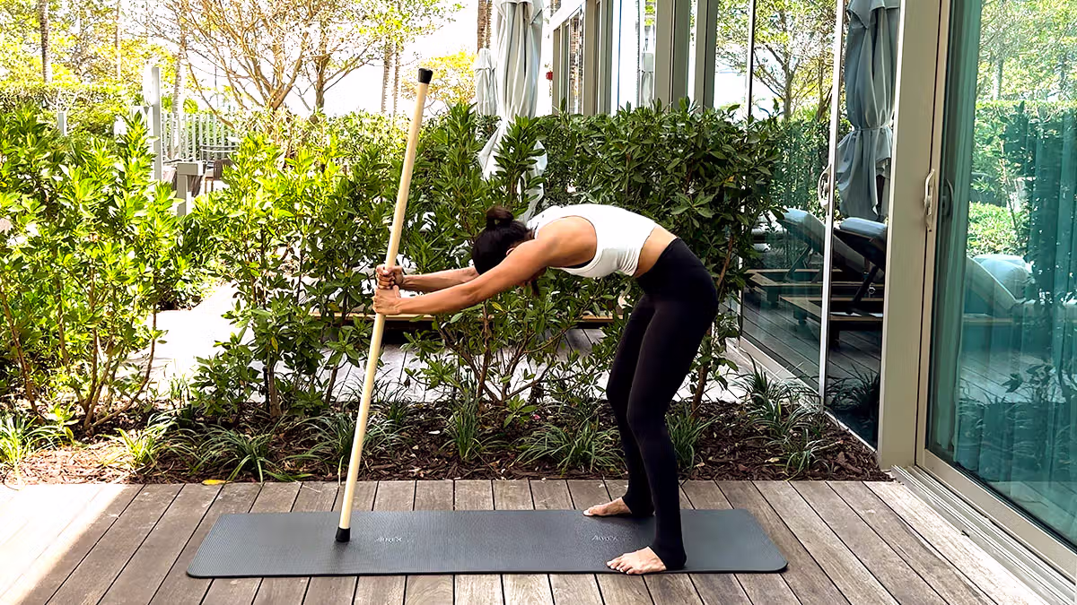 Standing cat-cow stretch using a mobility stick to mobilize the spine and improve flexibility