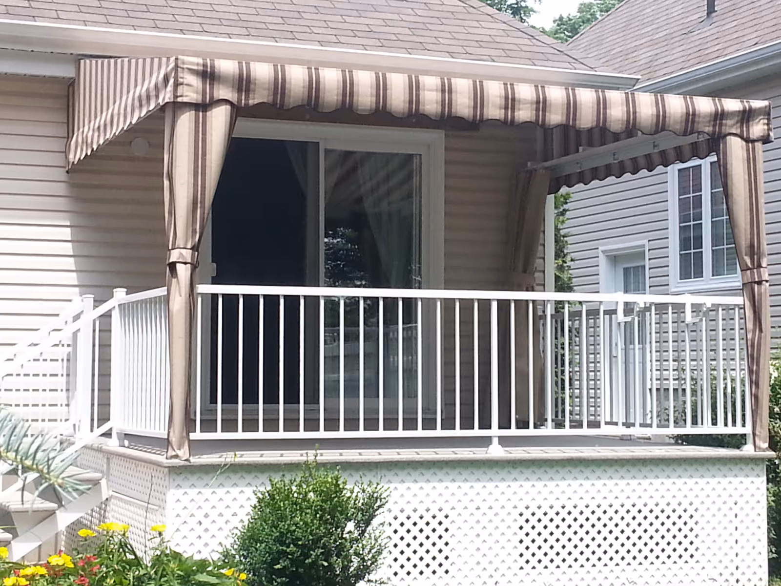 Small residential porch with a striped fabric awning, white railing, and sliding glass door.
