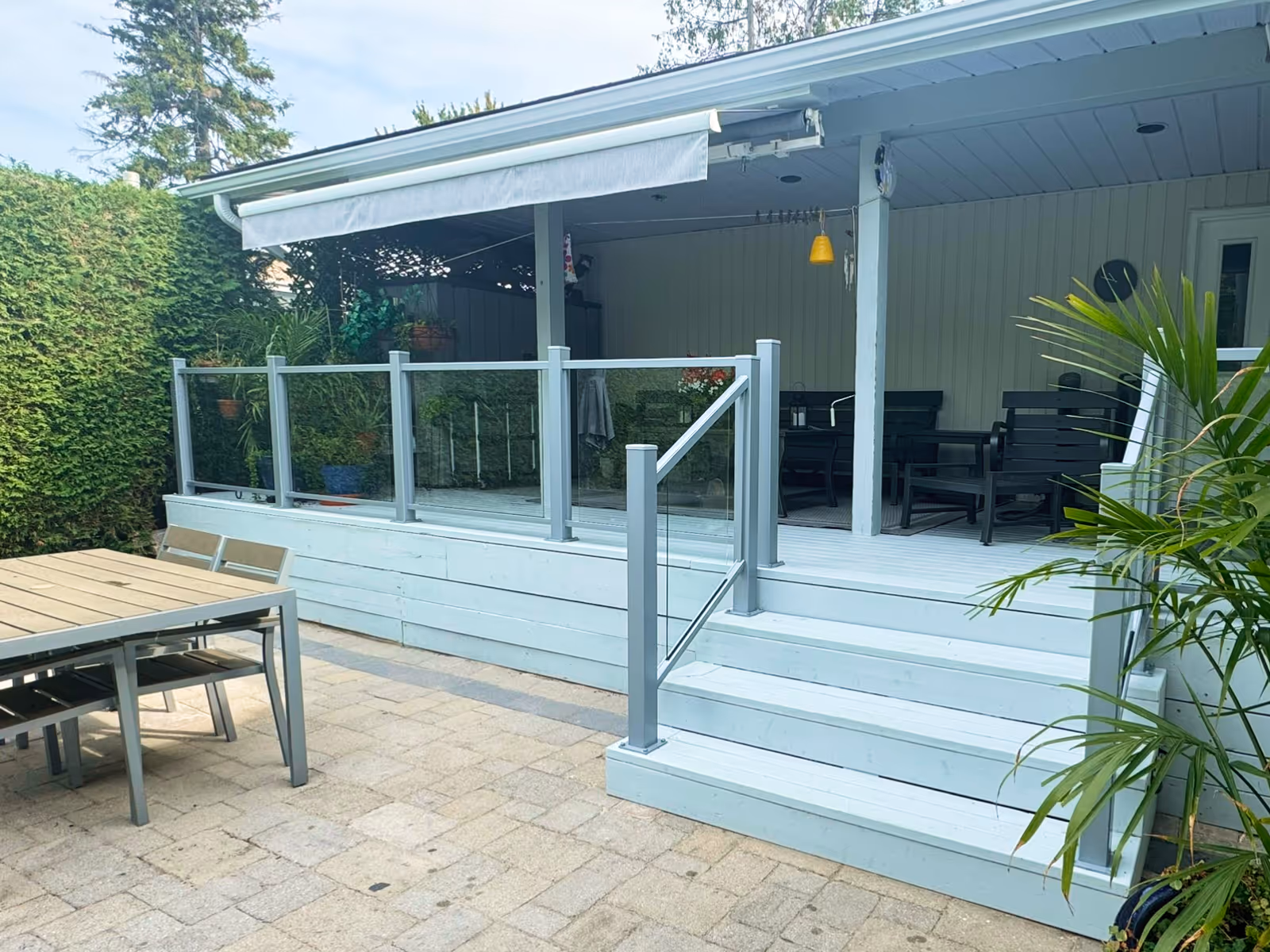 Covered porch with glass-paneled railing and retractable awning partially extended.
