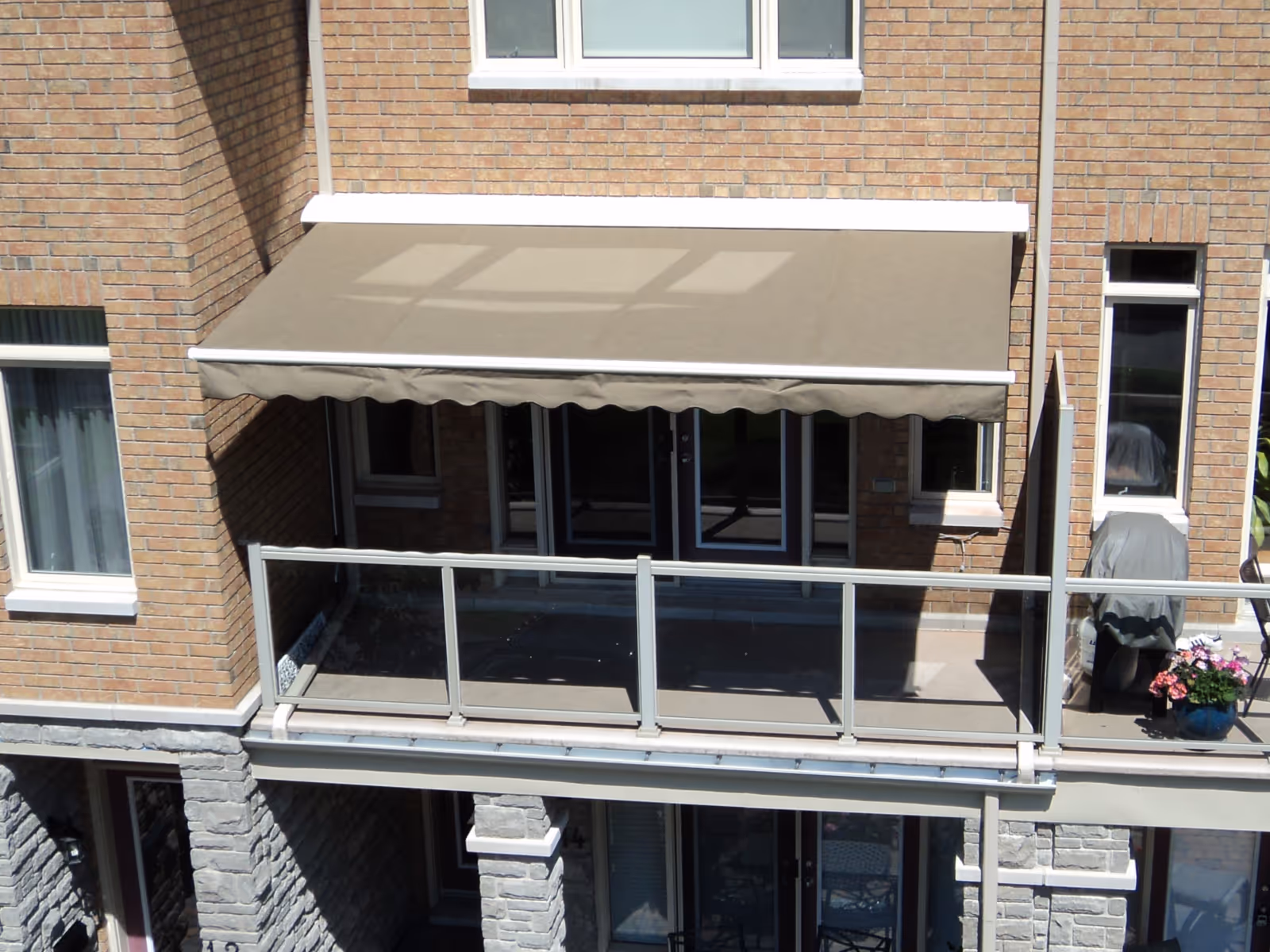 Beige retractable awning on a brick rowhouse.