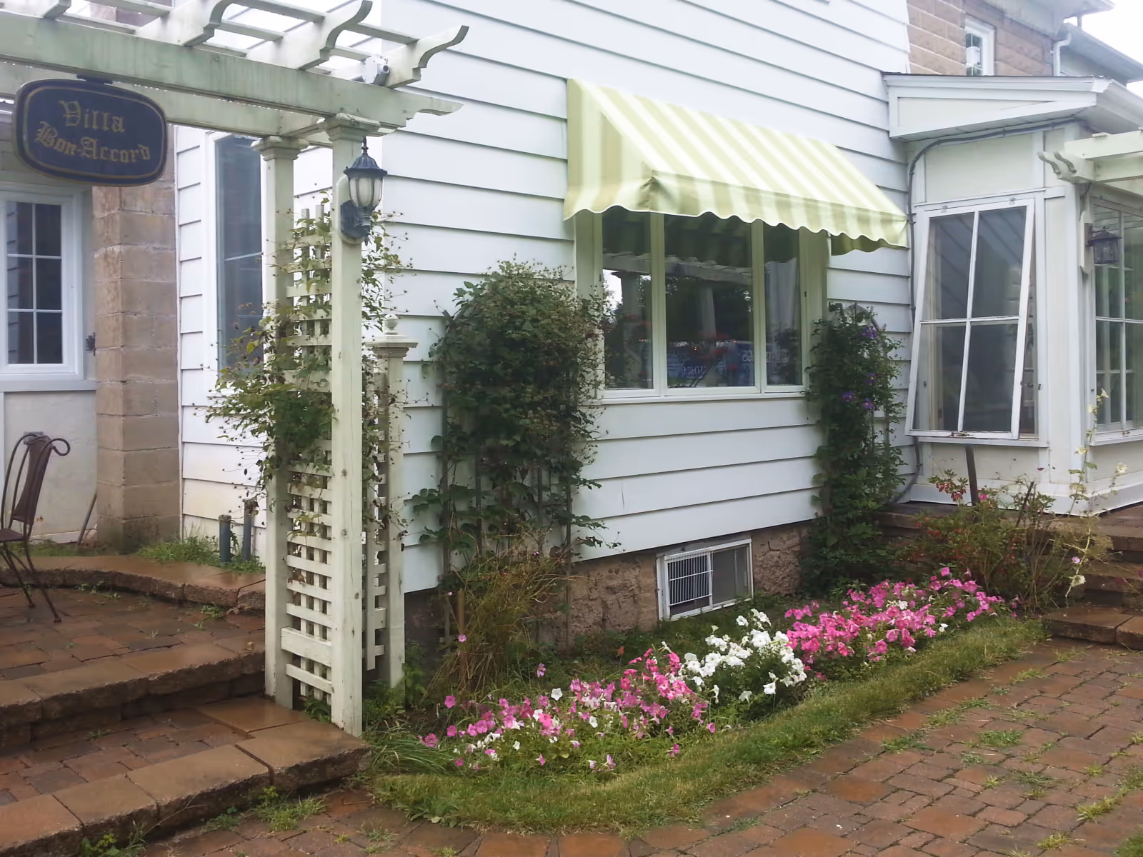 Green striped window awning on an old white house with white siding.