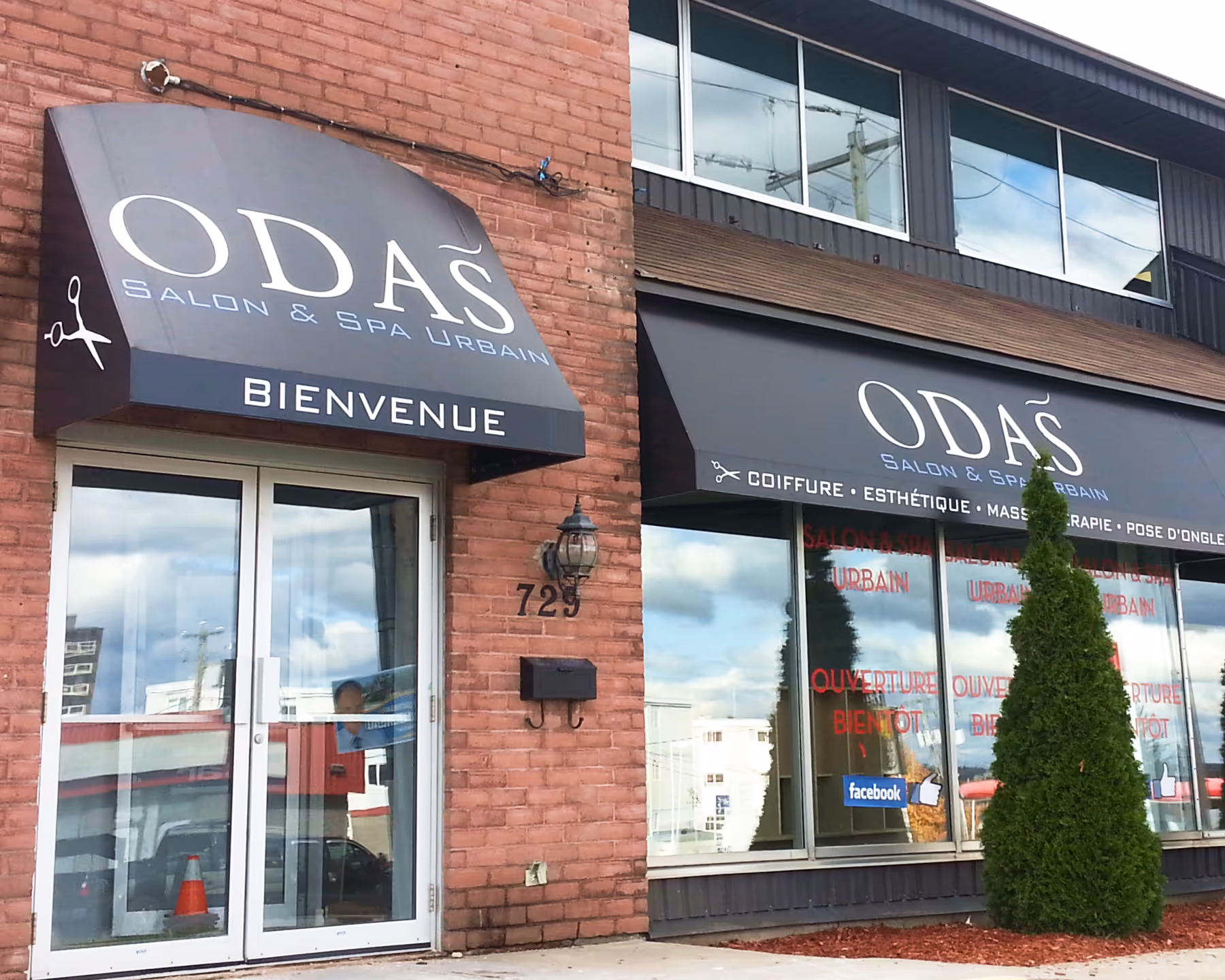 A door and a window of a salon with awnings bearing the business' name hanging above.