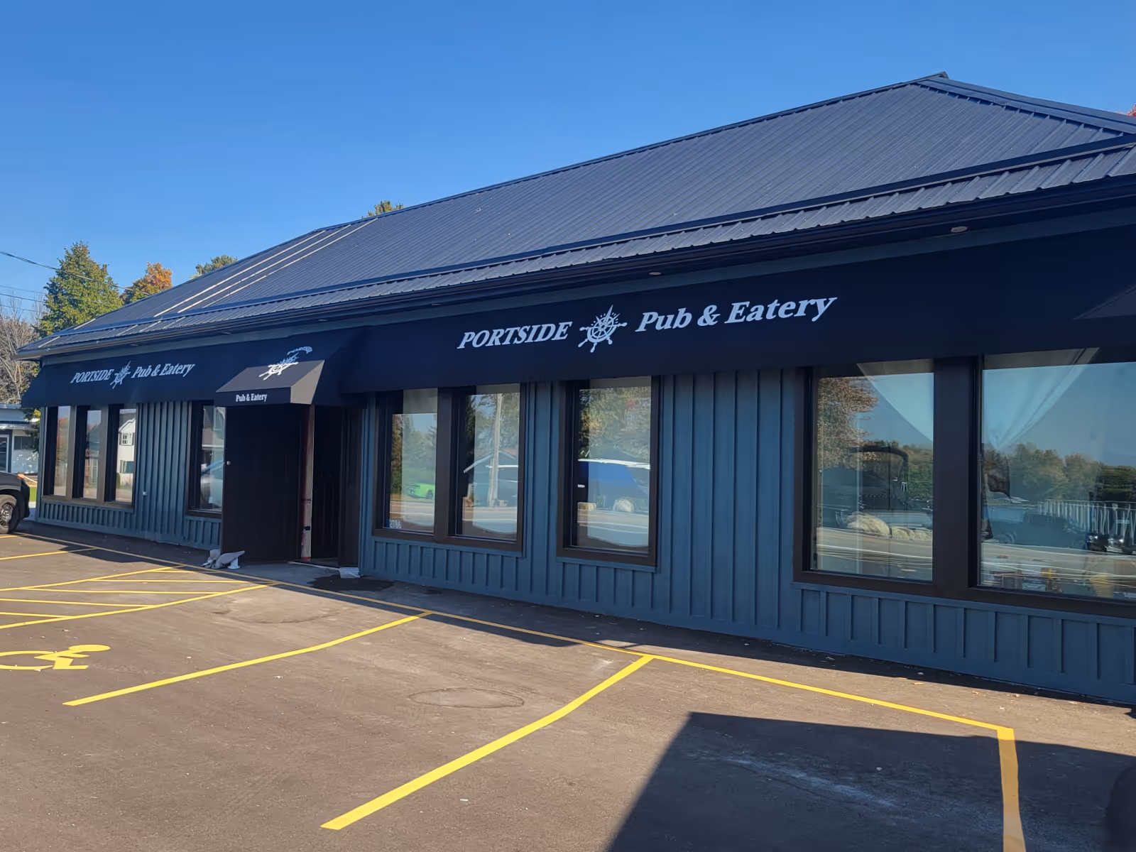 Exterior of Portside Pub & Eatery with black branded awnings that span the width of the restaurant.