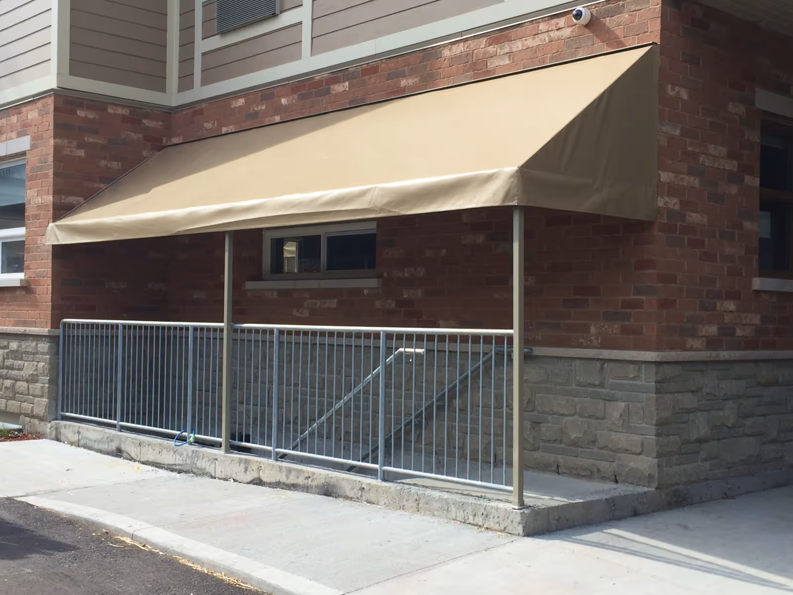 Beige vinyl awning over a concrete stairwell entrance leading underground.