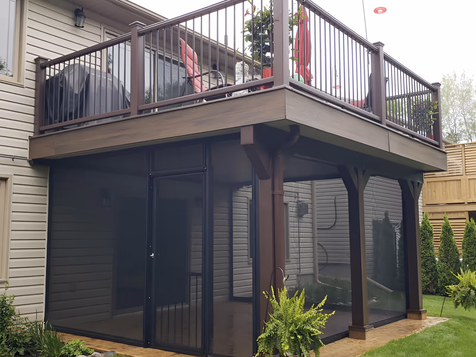 Tension screens enclose a stone patio situated underneath a second-floor deck.