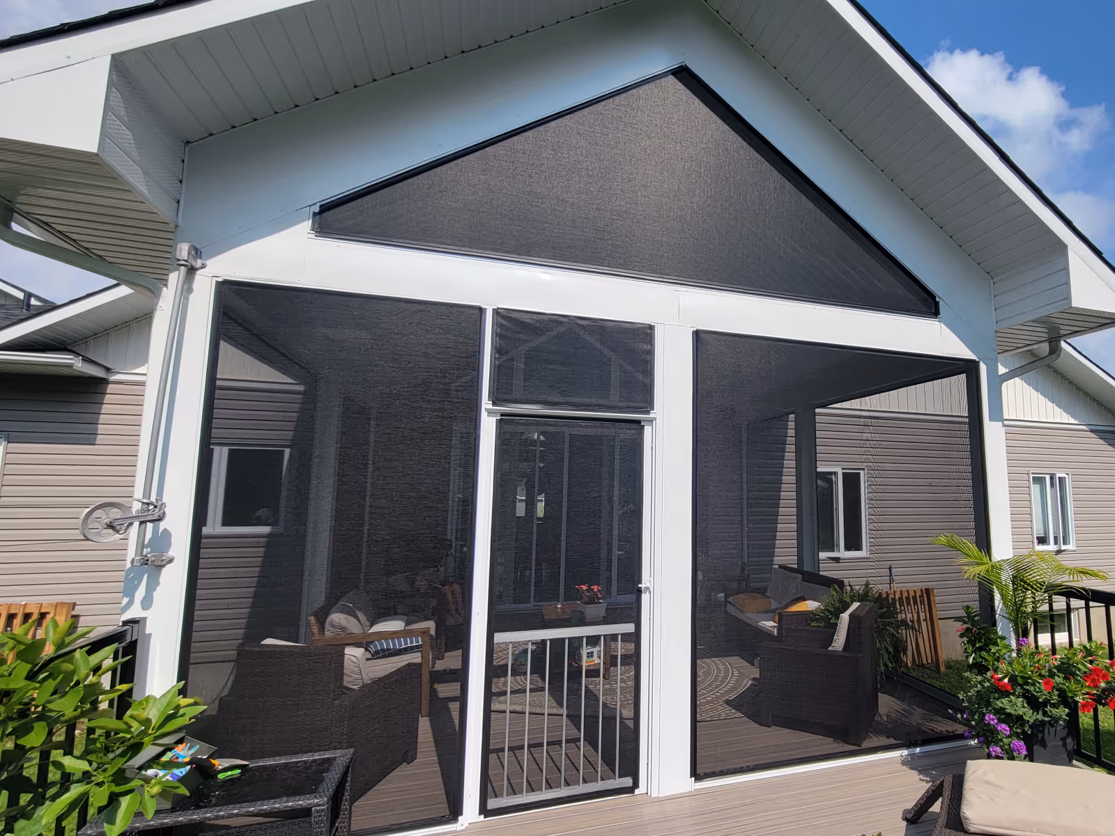 Covered porch with peaked roof enclosed with white-framed tension screens.