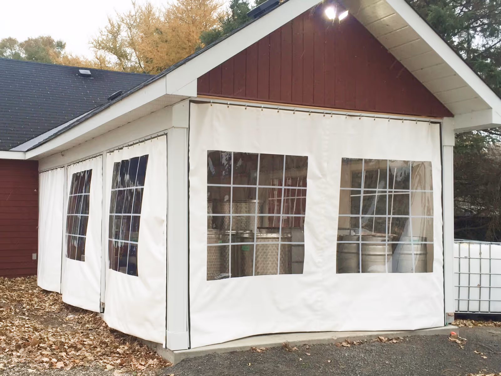 White vinyl curtains with clear windows surround a brown barn-style structure.