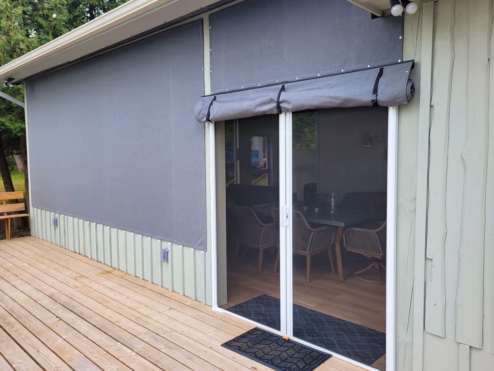 A grey fabric panel is rolled up and held in place with straps and buckles to reveal a screened patio door.