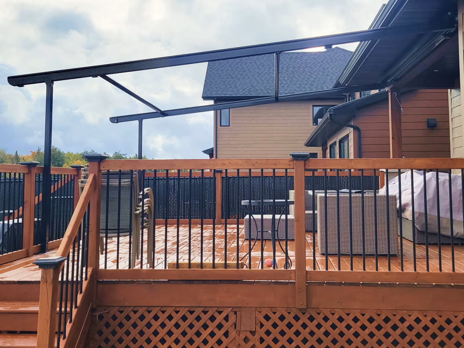 A Pergolino awning with black metal frame and fabric completely retracted over a wooden deck.