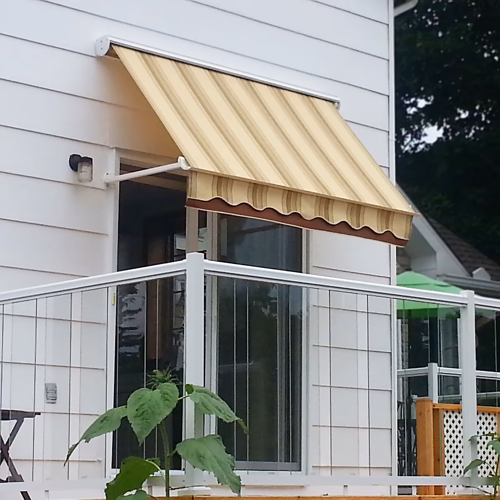 Ochre and brown striped awning installed above a glass patio door on a white house.