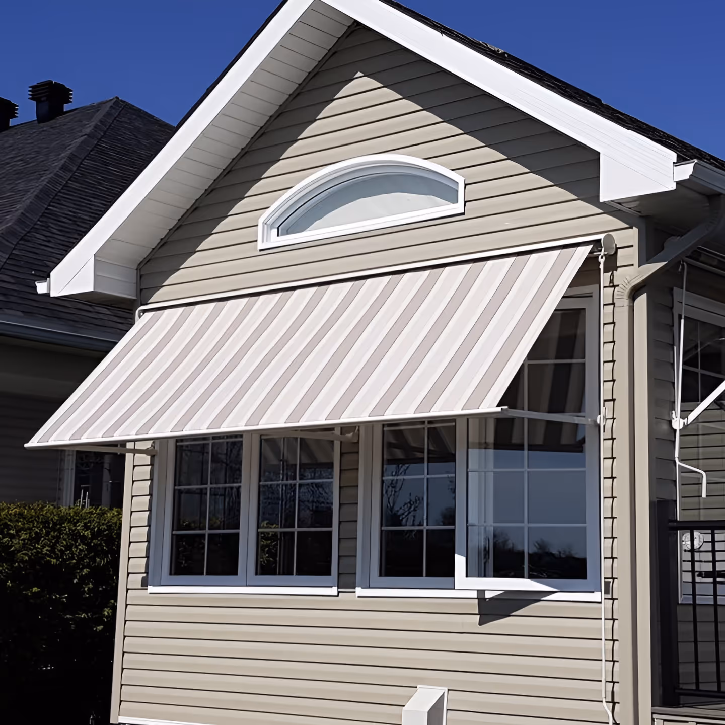 A beige and white striped awning over a window spanning the narrow end of a mobile home.