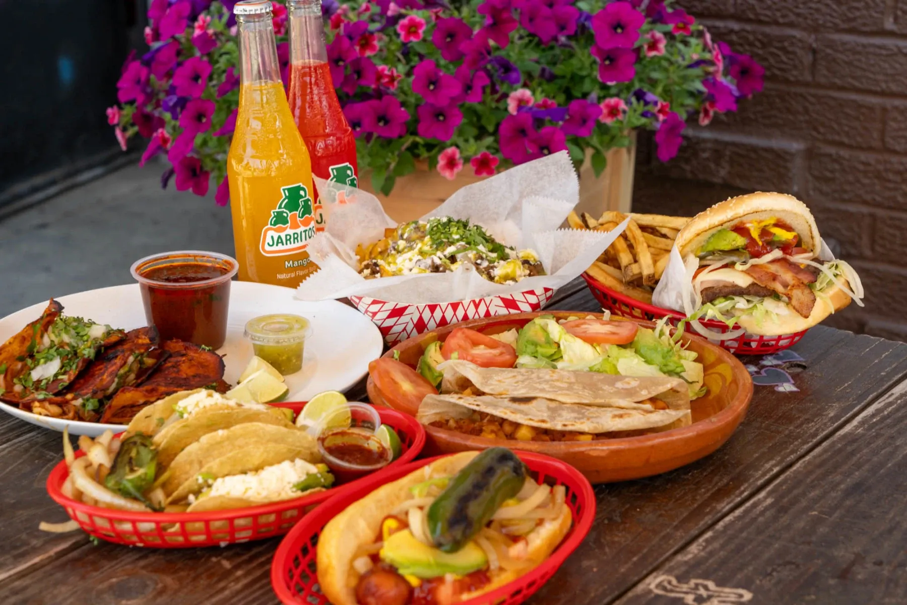 A table full of food and drinks with a jar of Jarritos soda.