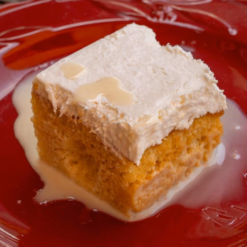 A piece of cake with white frosting on a red plate.