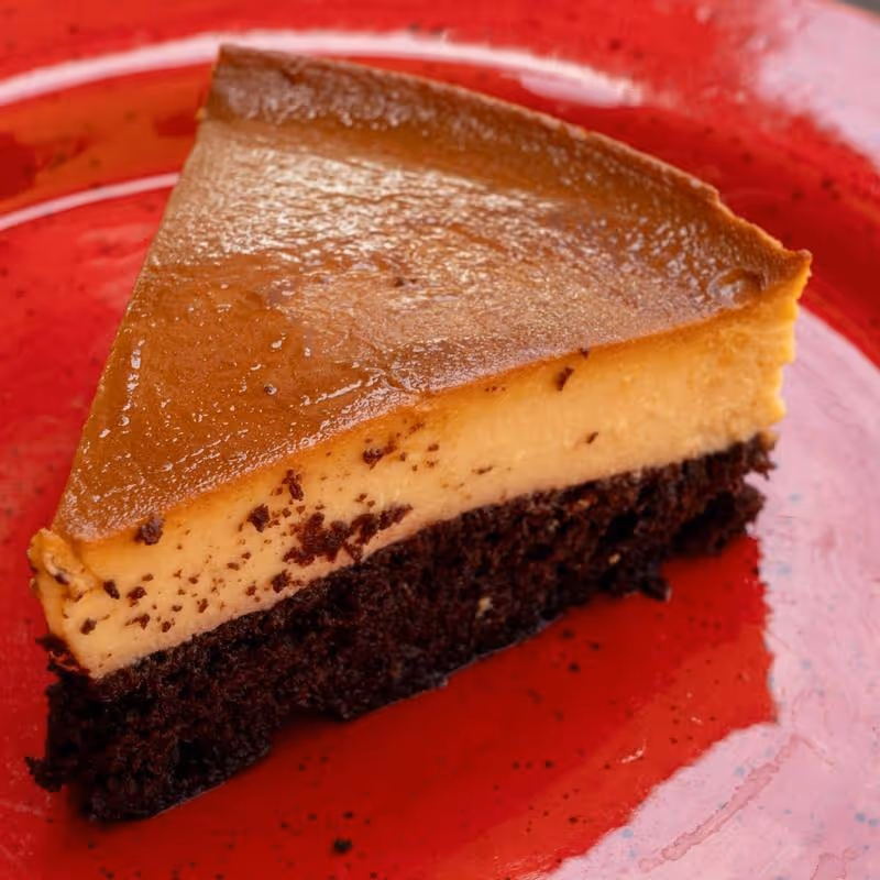 A slice of chocolate cake on a red plate.