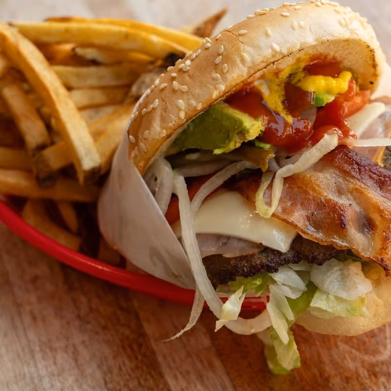 A burger with lettuce, tomato, and bacon on a bun.