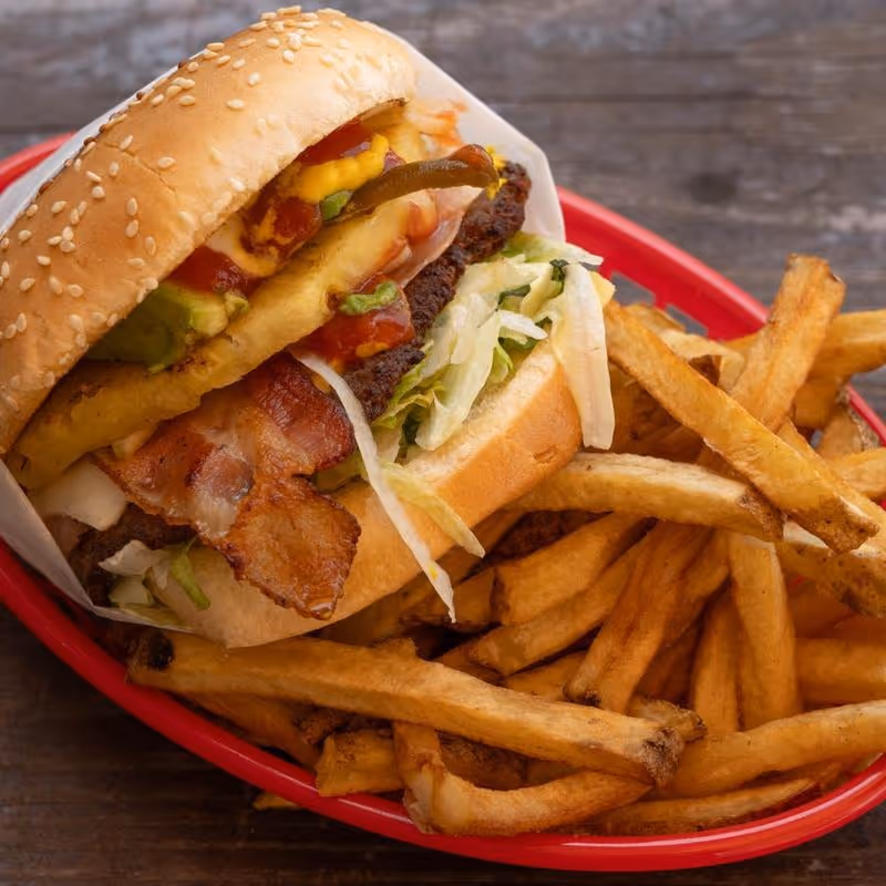 A large hamburger with bacon and lettuce on a bun.