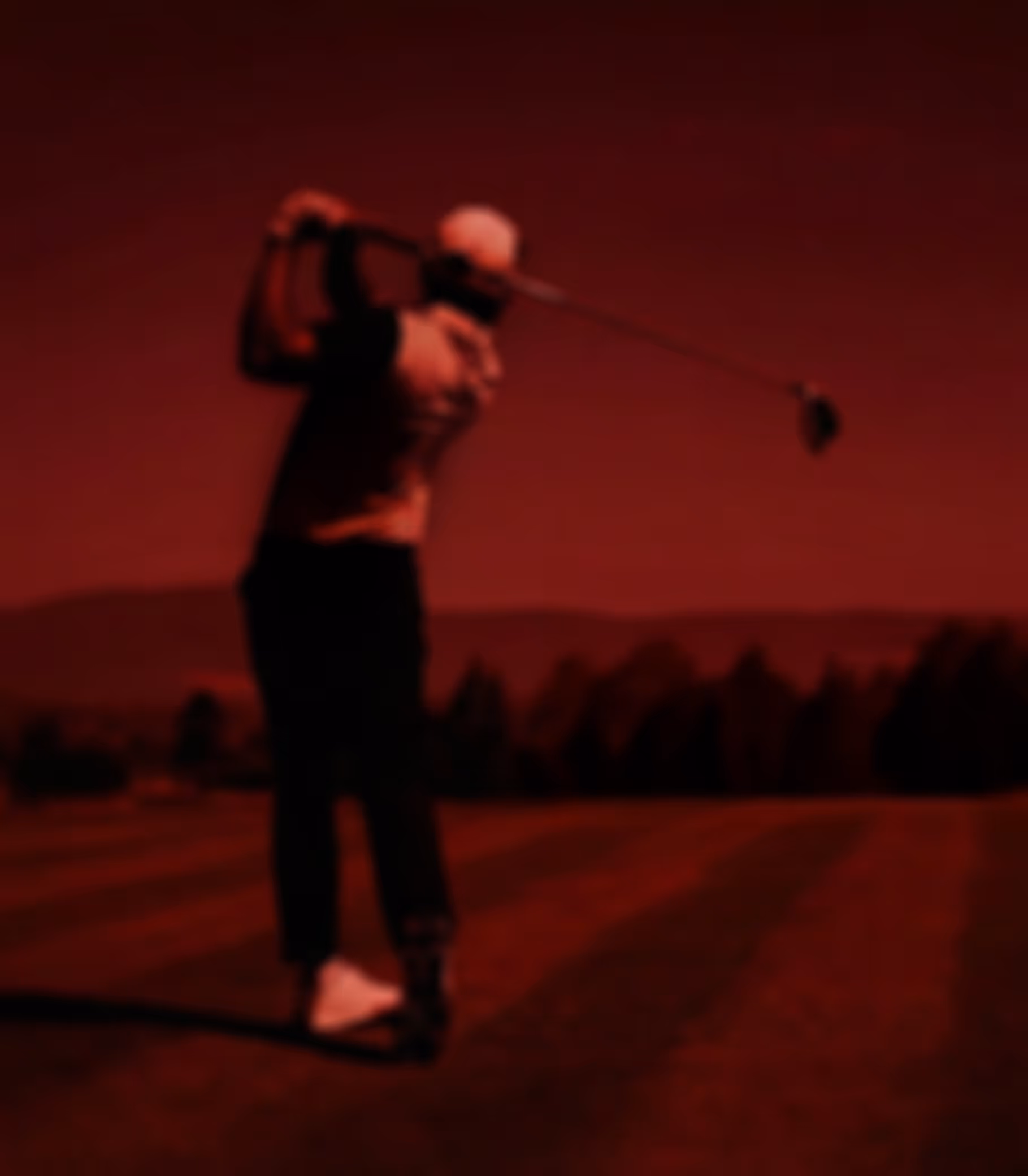 Silhouette of a golfer mid-swing against a red gradient background.