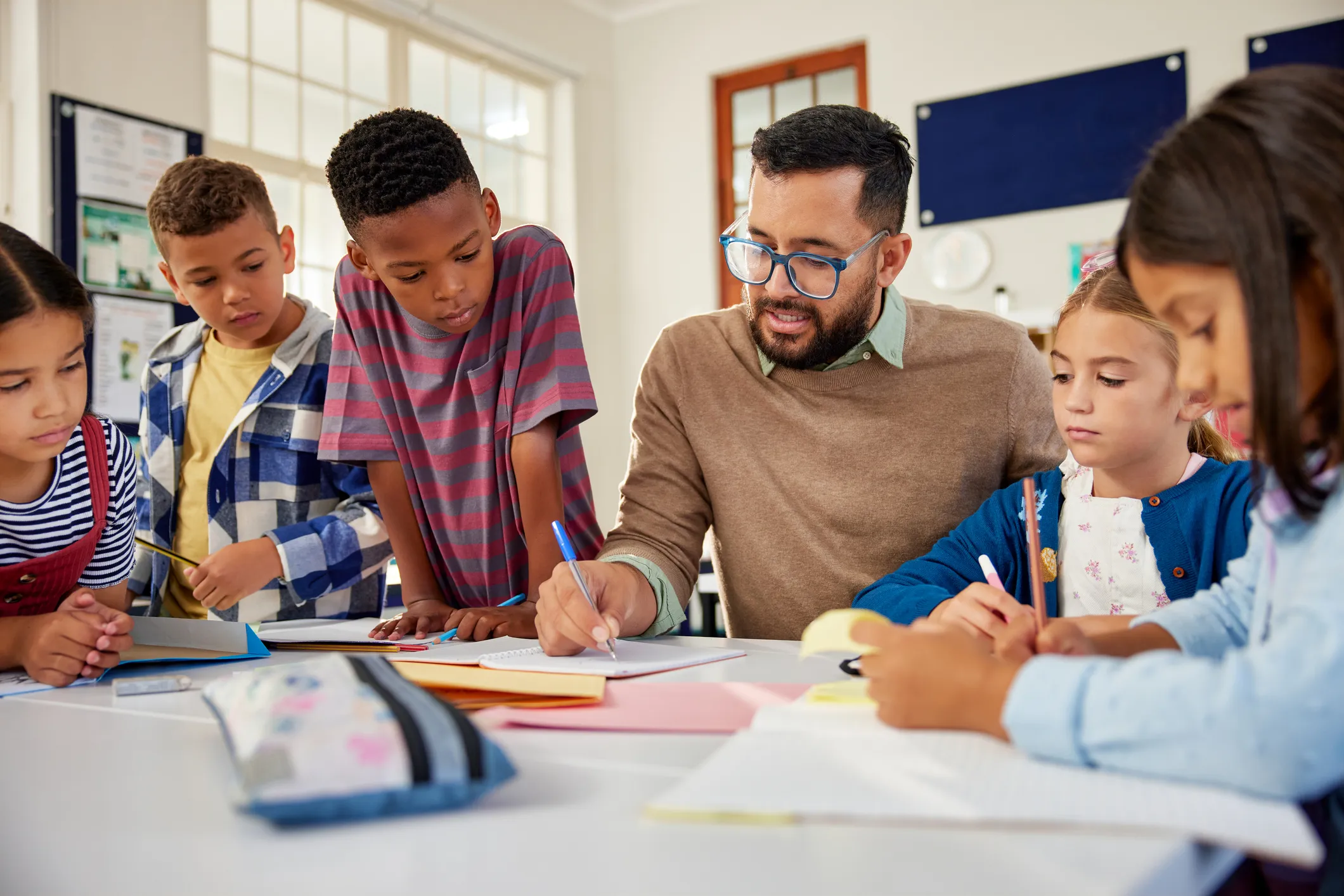 iStock 2160438108 Elem TeacherHelpingStudentsAtTable