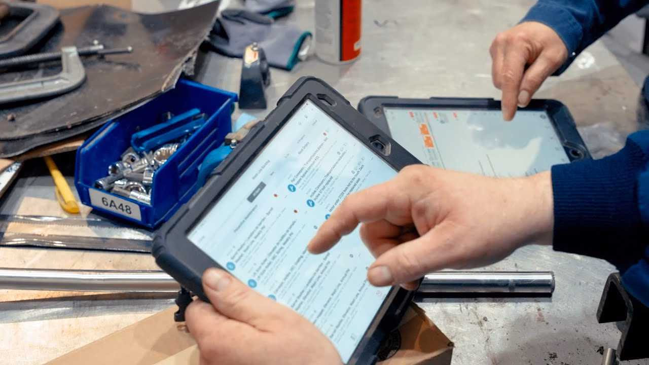 Close-up of a worker using a rugged tablet to review maintenance or reliability data beside industrial tools.