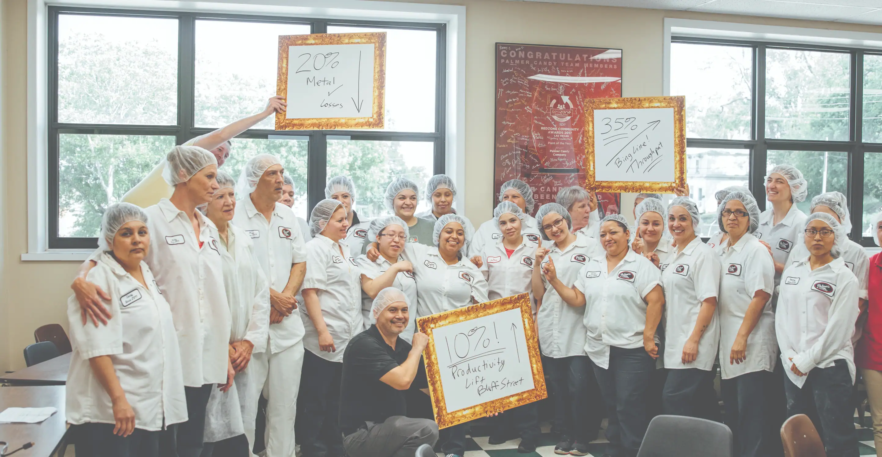 Palmer candy employees holding boards with success metrics from working with Redzone